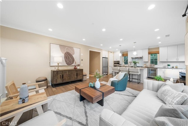 living room featuring beverage cooler, light wood finished floors, baseboards, and recessed lighting