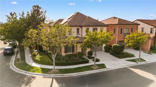 view of front of house with a garage, concrete driveway, a tile roof, and stucco siding