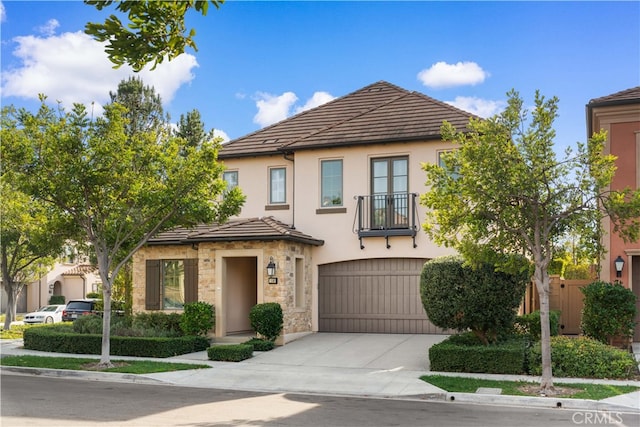 view of front facade with stucco siding, concrete driveway, a garage, stone siding, and a tiled roof