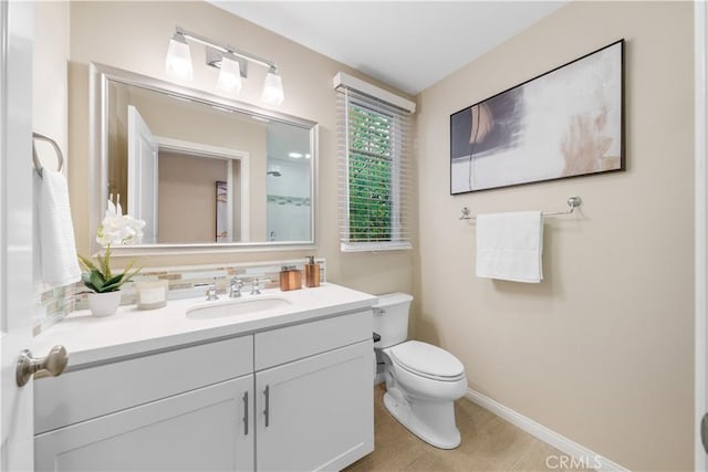 bathroom with toilet, decorative backsplash, vanity, and baseboards