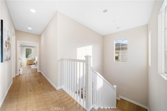 hall featuring recessed lighting, baseboards, light wood-style flooring, and an upstairs landing