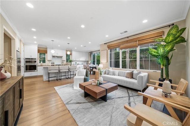 living area with light wood finished floors, visible vents, ornamental molding, and recessed lighting