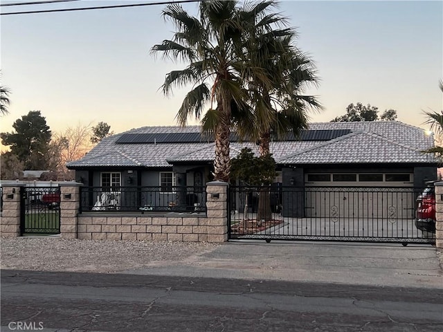 view of front of house with a fenced front yard, solar panels, a tile roof, driveway, and a gate