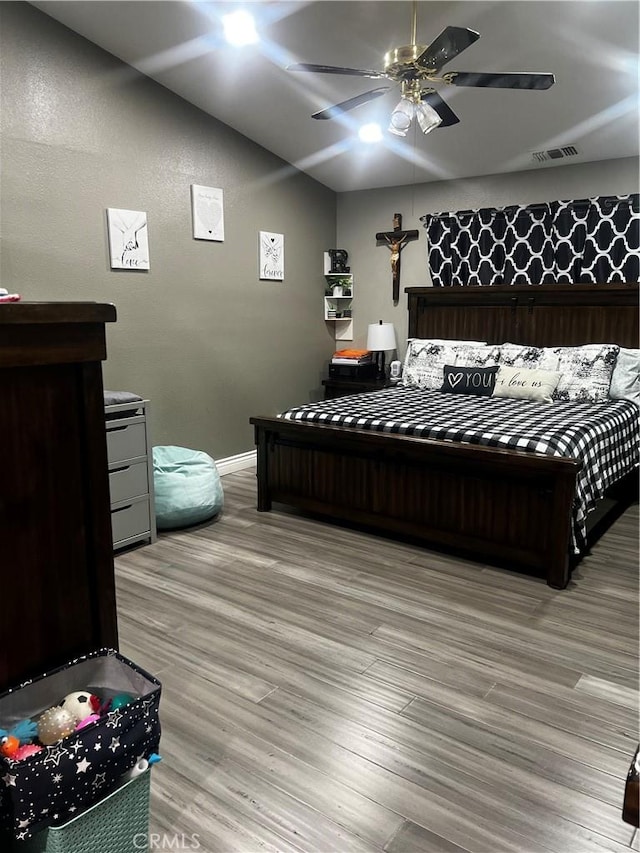 bedroom featuring visible vents, light wood-style flooring, a ceiling fan, vaulted ceiling, and baseboards