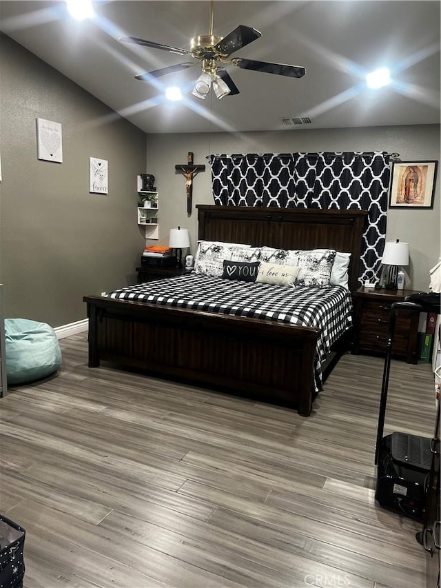 bedroom with a ceiling fan, visible vents, vaulted ceiling, baseboards, and light wood-type flooring