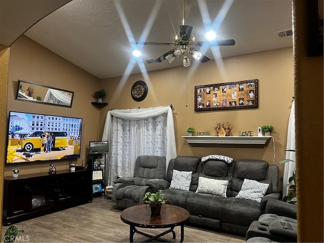 living area featuring lofted ceiling, light wood finished floors, visible vents, and a ceiling fan