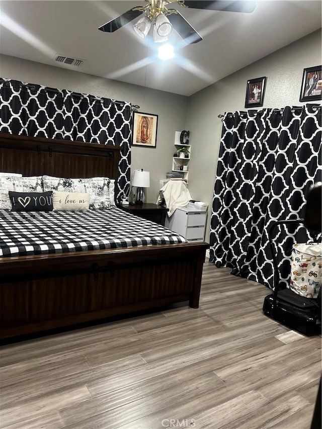 bedroom featuring a ceiling fan, visible vents, and light wood-style flooring