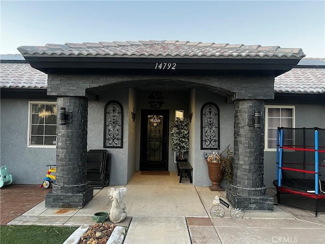 entrance to property featuring a tiled roof and stucco siding