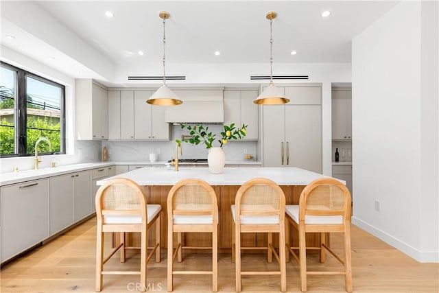 4435 Katherine Ave, Sherman Oaks, CA 91423 - kitchen featuring decorative backsplash, light countertops, a center island with sink, light wood-style flooring, and recessed lighting