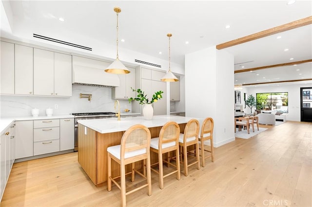 4435 Katherine Ave, Sherman Oaks, CA 91423 - kitchen with recessed lighting, light countertops, a kitchen island with sink, tasteful backsplash, and custom exhaust hood