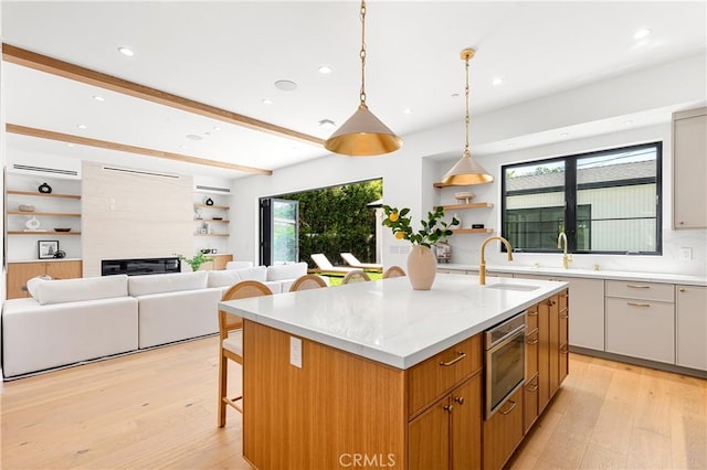 4435 Katherine Ave, Sherman Oaks, CA 91423 - kitchen with light wood-type flooring, a kitchen island with sink, a fireplace, and a sink