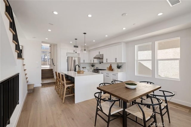 dining space with light wood-type flooring, visible vents, and recessed lighting