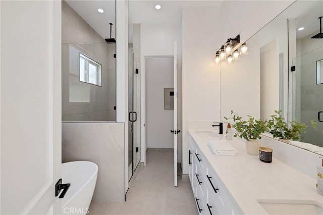 full bathroom with double vanity, a freestanding bath, a shower stall, a sink, and recessed lighting