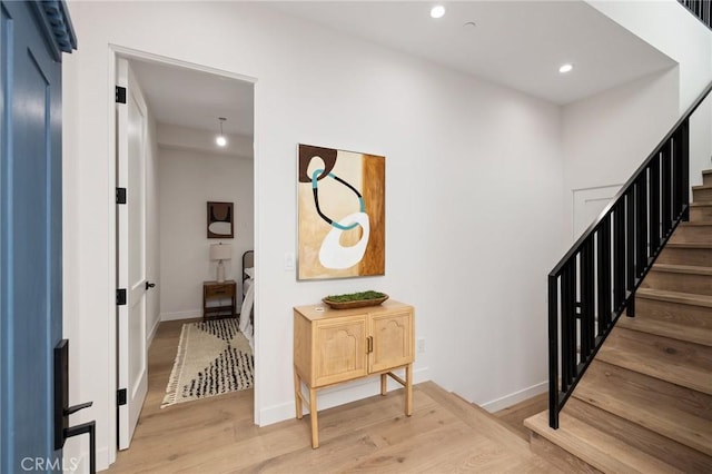 interior space featuring light wood finished floors, stairs, baseboards, and recessed lighting