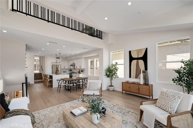 living room with vaulted ceiling with beams, light wood finished floors, baseboards, and recessed lighting