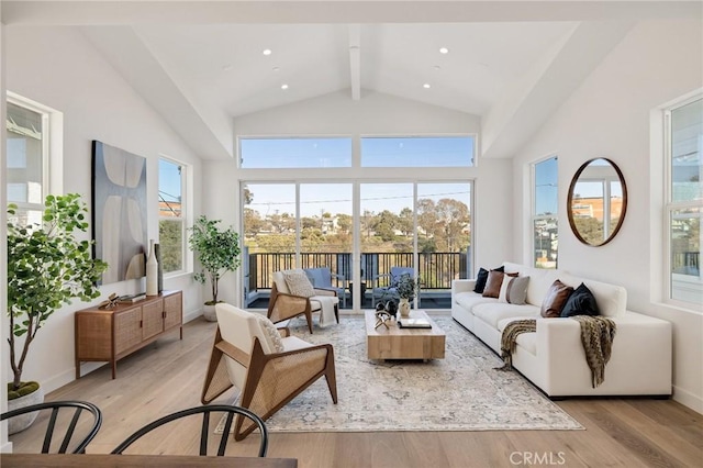 living room with light wood-style floors, beam ceiling, high vaulted ceiling, and baseboards