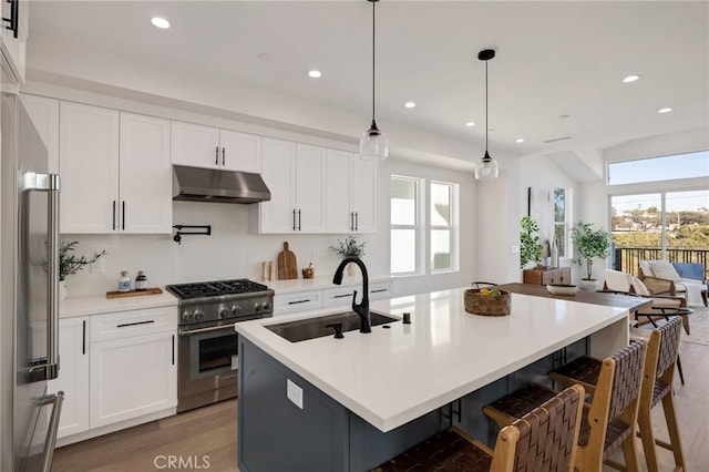 kitchen featuring high quality appliances, open floor plan, decorative light fixtures, light countertops, and under cabinet range hood