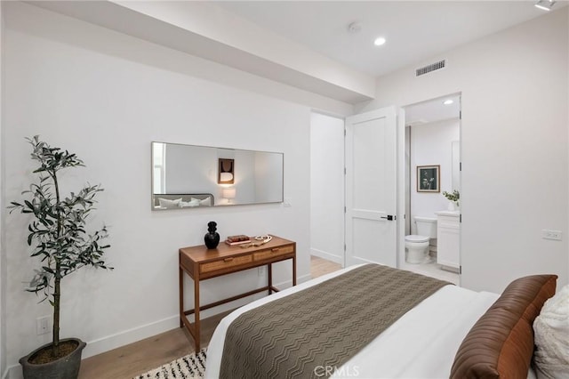 bedroom with recessed lighting, visible vents, light wood-style flooring, ensuite bath, and baseboards