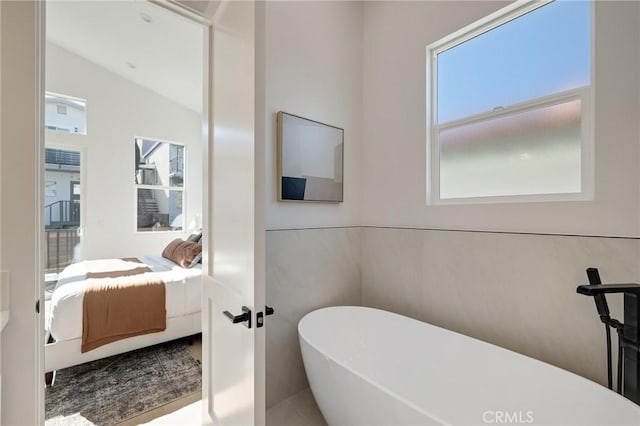 ensuite bathroom with a healthy amount of sunlight, a soaking tub, and ensuite bathroom