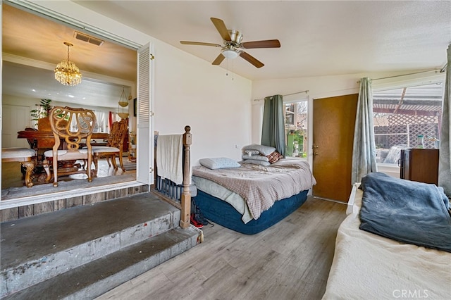 bedroom with visible vents, an inviting chandelier, and wood finished floors