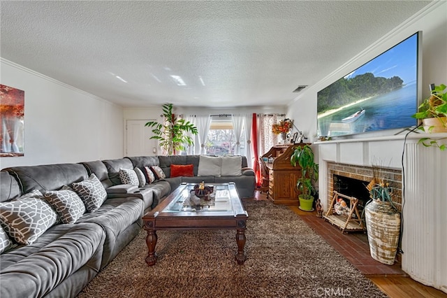 living room with visible vents, ornamental molding, wood finished floors, a textured ceiling, and a fireplace