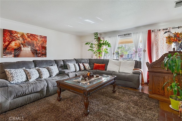 living area with a textured ceiling, wood finished floors, visible vents, and crown molding