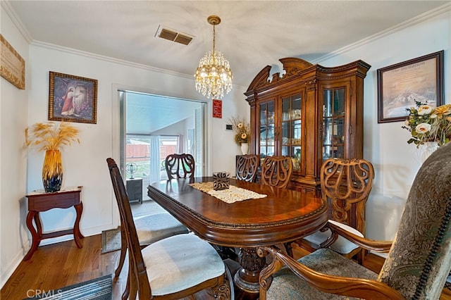 dining space with crown molding, visible vents, an inviting chandelier, wood finished floors, and baseboards