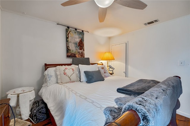 bedroom with visible vents, wood finished floors, a ceiling fan, and ornamental molding