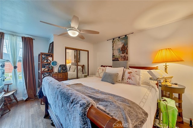 bedroom with a closet, a ceiling fan, wood finished floors, and ornamental molding