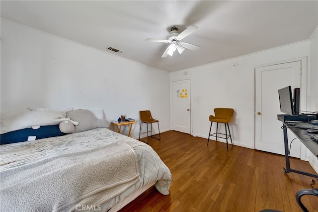 bedroom featuring crown molding, visible vents, a ceiling fan, wood finished floors, and baseboards