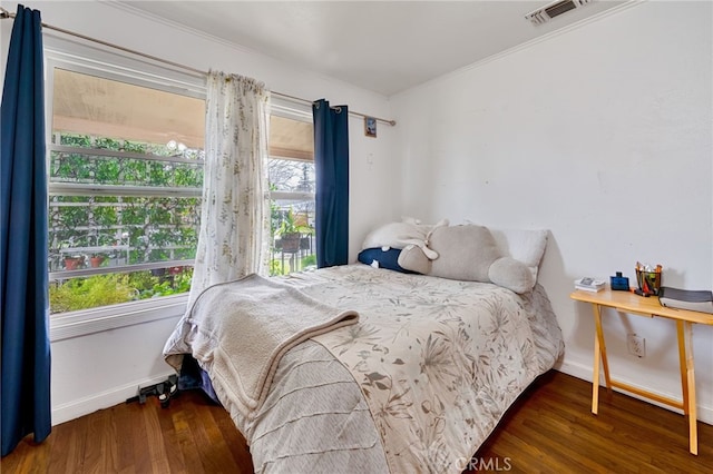 bedroom featuring ornamental molding, multiple windows, and wood finished floors