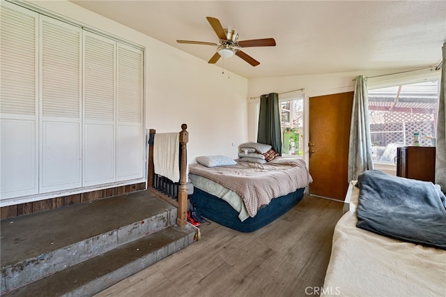 bedroom with a ceiling fan, vaulted ceiling, and wood finished floors