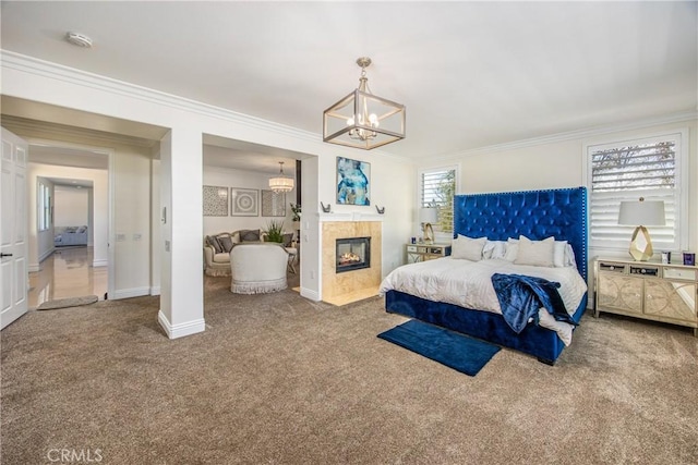 bedroom featuring a tile fireplace, crown molding, carpet flooring, baseboards, and an inviting chandelier