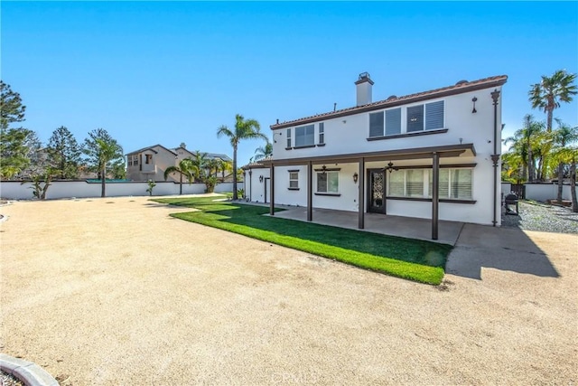 rear view of property with a ceiling fan, a chimney, fence, a patio area, and stucco siding