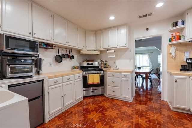 kitchen with white cabinets, stainless steel appliances, under cabinet range hood, and visible vents