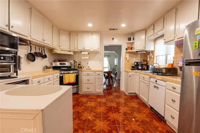 kitchen with visible vents, tasteful backsplash, appliances with stainless steel finishes, under cabinet range hood, and open shelves