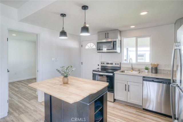 kitchen featuring stainless steel appliances, a kitchen island, a sink, and light wood-style floors