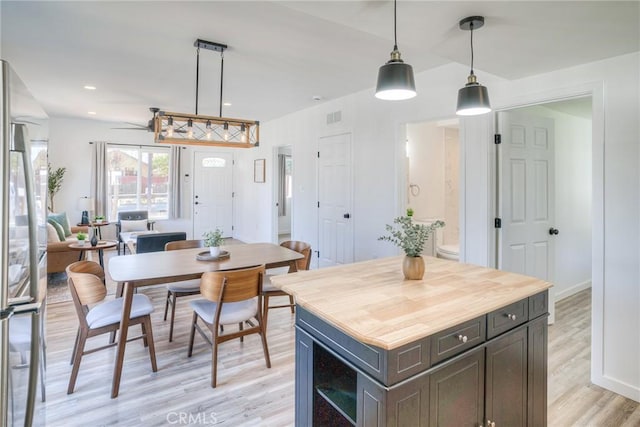 kitchen with hanging light fixtures, stainless steel fridge, a kitchen island, and light wood-style floors