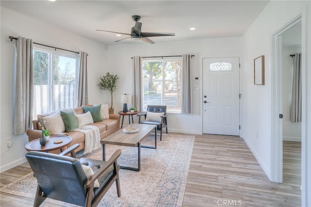 living room with light wood-style floors, baseboards, and a wealth of natural light