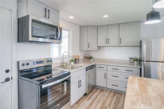 kitchen with pendant lighting, light countertops, a sink, and stainless steel appliances