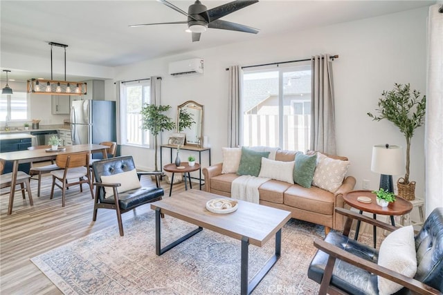 living area featuring light wood-style flooring, ceiling fan, and a wall mounted air conditioner