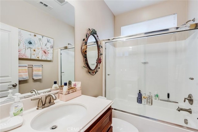 bathroom featuring toilet, vanity, visible vents, and enclosed tub / shower combo