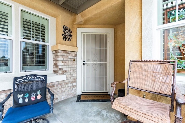 property entrance featuring brick siding and stucco siding