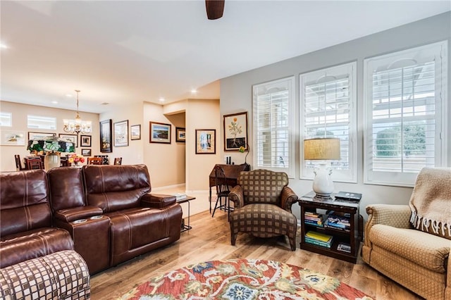 living room with baseboards, light wood finished floors, recessed lighting, and an inviting chandelier