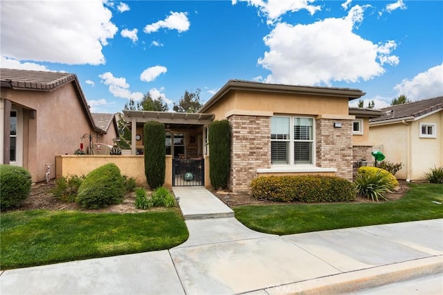 view of front of property featuring brick siding, a fenced front yard, a gate, and stucco siding