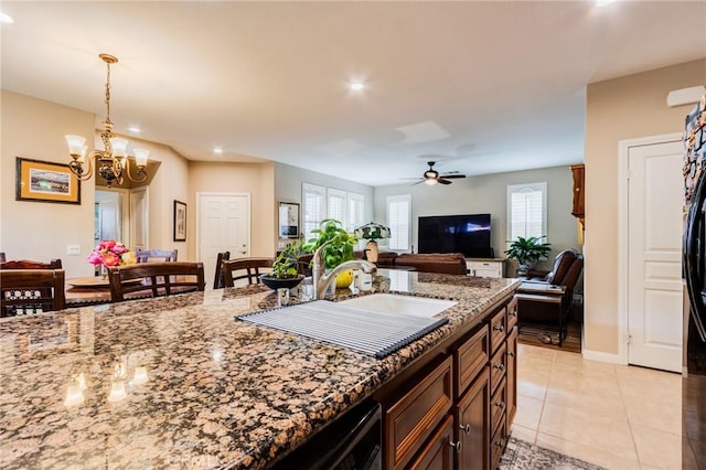 kitchen featuring light tile patterned floors, stone countertops, open floor plan, and ceiling fan with notable chandelier