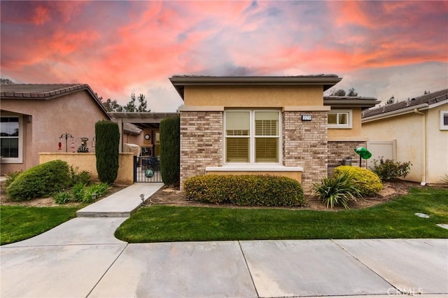 view of front of house featuring brick siding, fence, a gate, and stucco siding