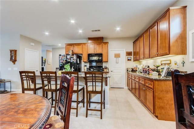 kitchen featuring brown cabinets, black appliances, and a kitchen breakfast bar