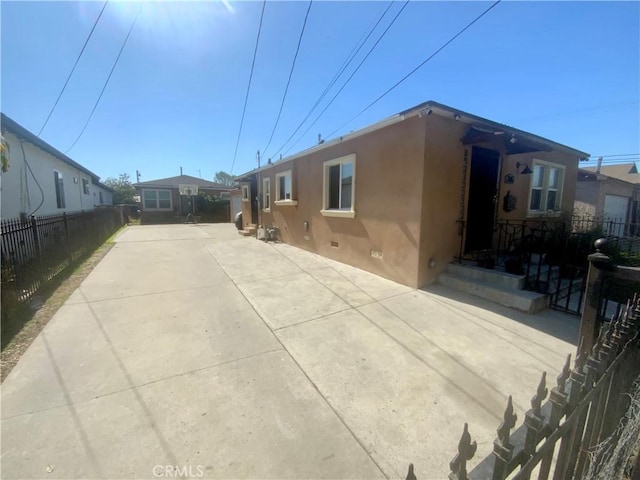 view of property exterior with crawl space, fence, and stucco siding