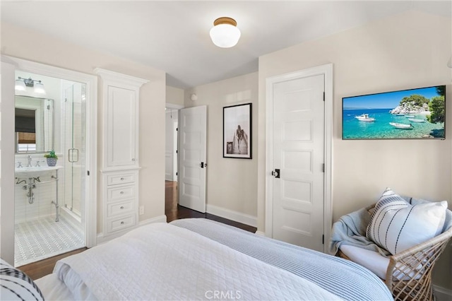 bedroom with dark wood-style floors, connected bathroom, and baseboards